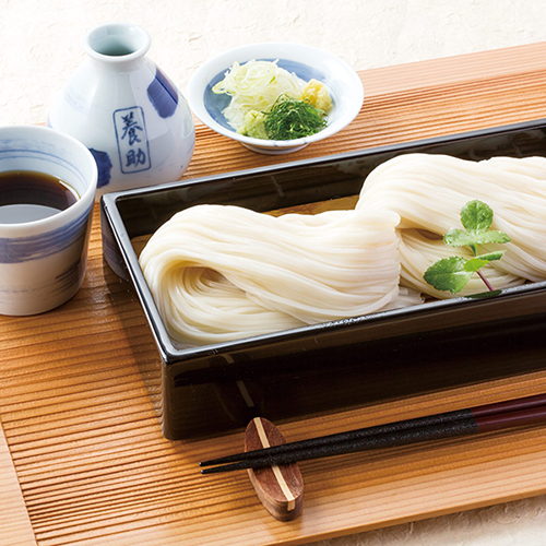 A beautifully arranged serving of chilled Inaniwa udon noodles placed on a bamboo seiro tray, presented with elegant Japanese tableware and tray.