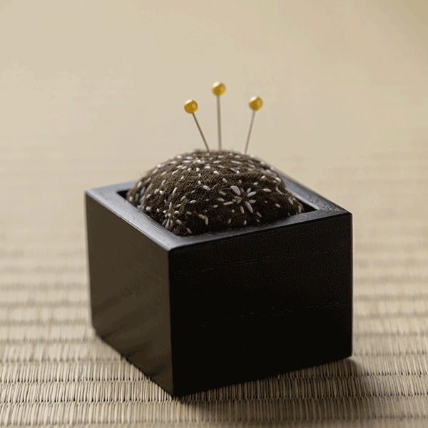 Hand-stitched Sashiko pin cushion with three pins inserted.
