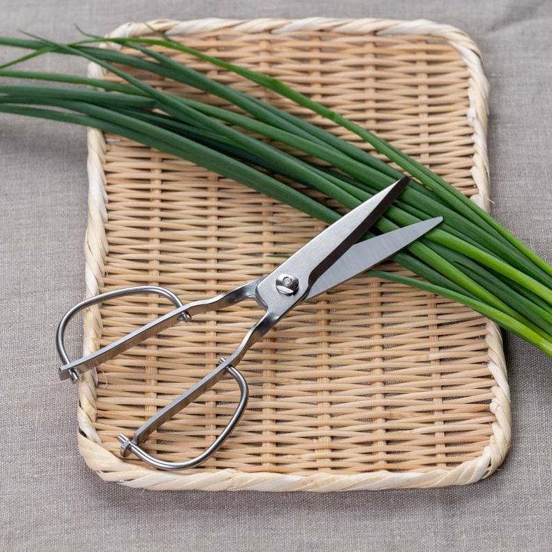 Toribe Designers Kitchen Scissors resting on a Japanese bamboo sieve with spring onions